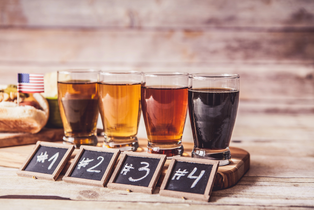 Four beer samples on wooden table with chalk signs.