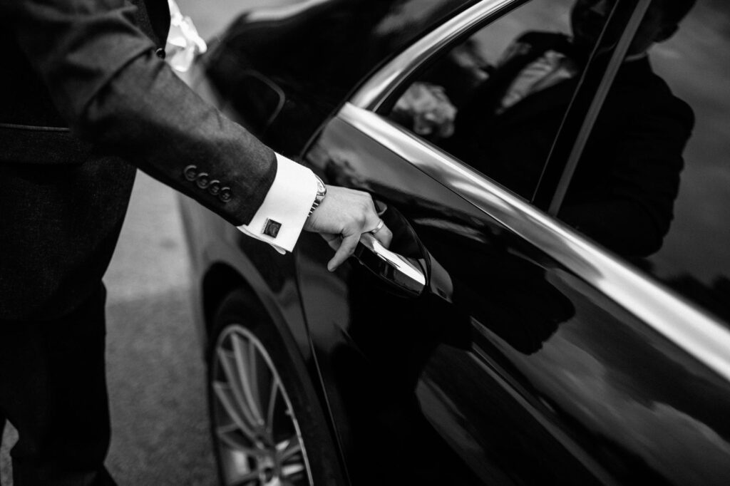 Person opening car door in formal attire.