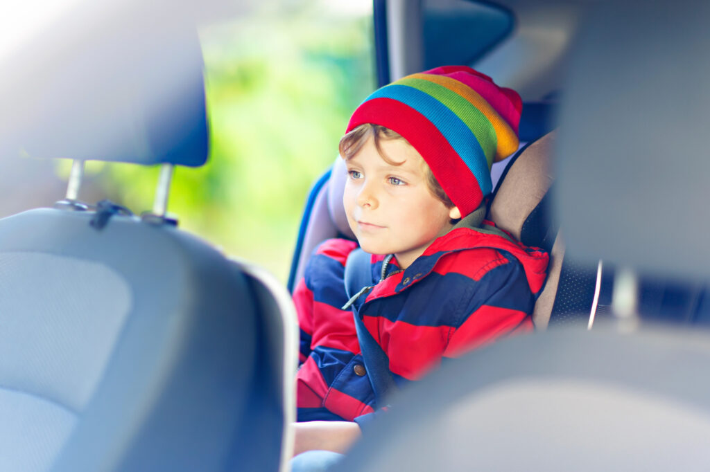 Child in colorful hat sitting in car seat.